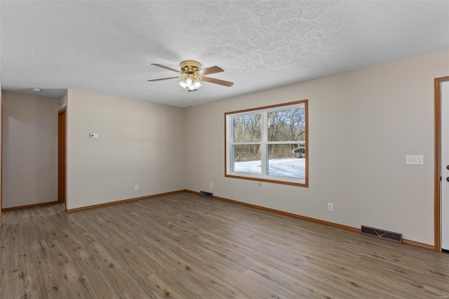 unfurnished room featuring visible vents, baseboards, and wood finished floors