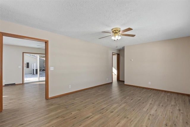 unfurnished room with a ceiling fan, a textured ceiling, baseboards, and wood finished floors