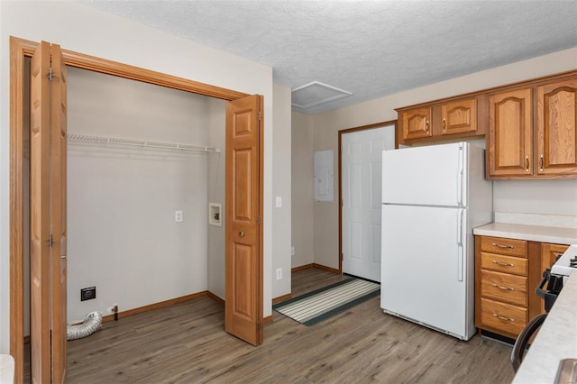 kitchen with brown cabinetry, freestanding refrigerator, light countertops, and light wood-style flooring