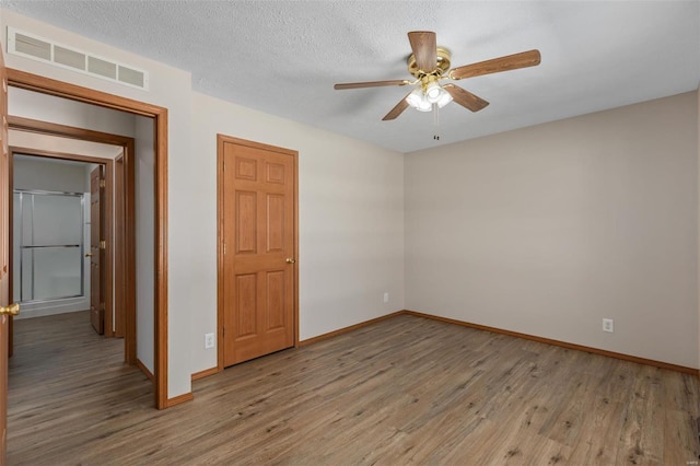 unfurnished bedroom with visible vents, a ceiling fan, a textured ceiling, wood finished floors, and baseboards