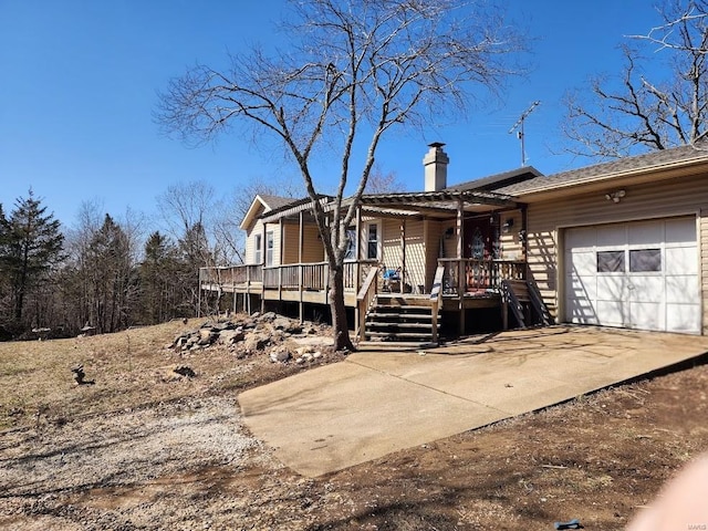 view of front facade featuring a garage, concrete driveway, and a chimney