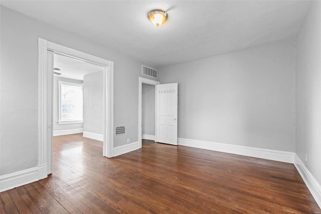 empty room featuring visible vents, baseboards, and wood-type flooring