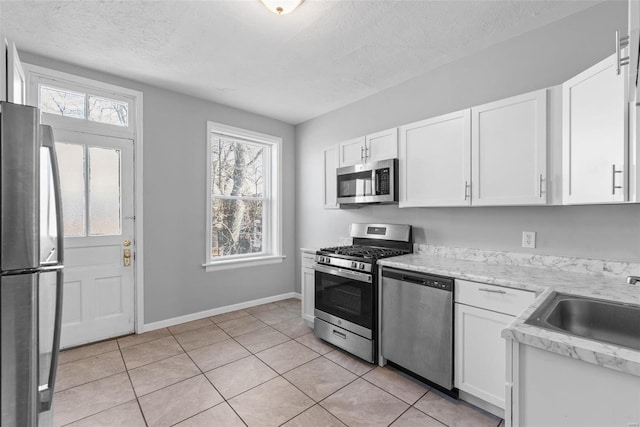 kitchen with a wealth of natural light, white cabinets, appliances with stainless steel finishes, and a textured ceiling