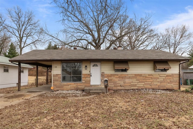 ranch-style house with an attached carport, a chimney, stone siding, and a shingled roof