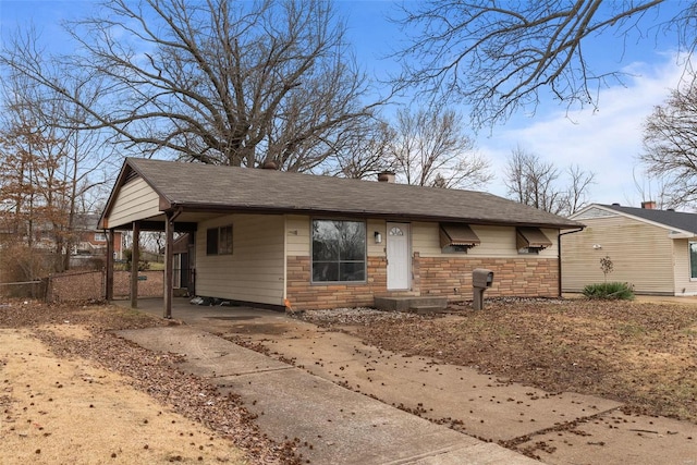 view of front facade with a carport, fence, stone siding, and roof with shingles