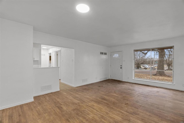 spare room with wood finished floors, visible vents, and baseboards