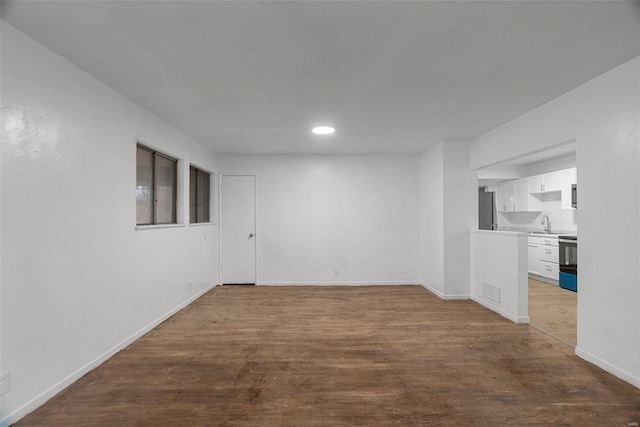 unfurnished room with visible vents, baseboards, recessed lighting, dark wood-style flooring, and a sink