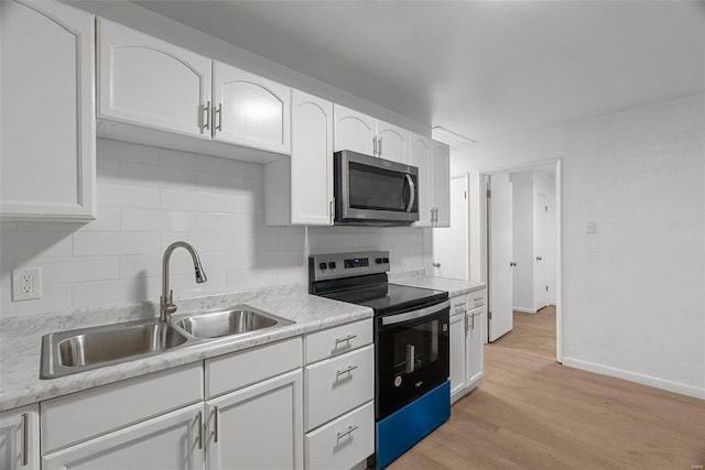 kitchen with tasteful backsplash, light wood-style flooring, appliances with stainless steel finishes, white cabinetry, and a sink