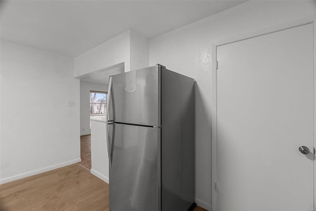 kitchen with light wood-style flooring, baseboards, and freestanding refrigerator