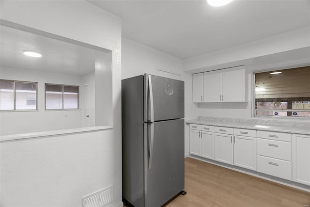 kitchen featuring visible vents, light countertops, freestanding refrigerator, light wood-style floors, and white cabinetry