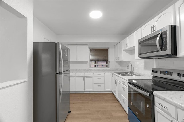 kitchen with a sink, stainless steel appliances, light wood-style floors, and white cabinets