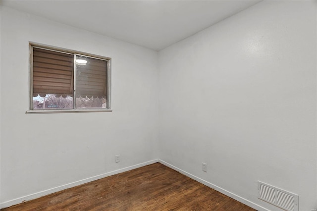 unfurnished room featuring dark wood-style floors, visible vents, and baseboards