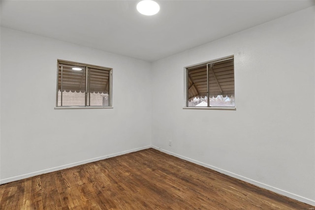 empty room featuring baseboards and dark wood-style floors