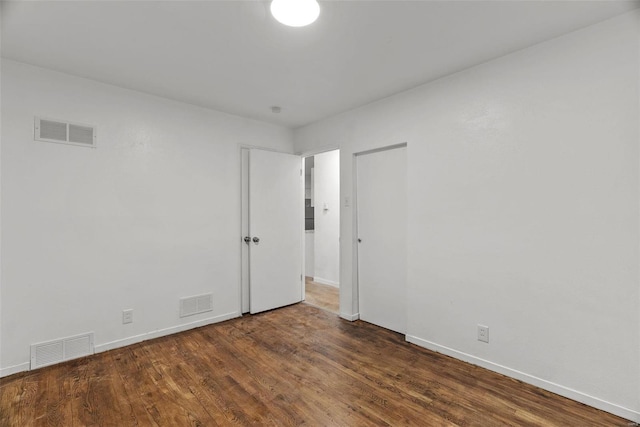 empty room featuring visible vents, baseboards, and wood finished floors