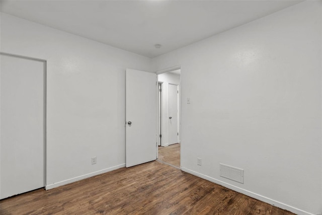 unfurnished bedroom featuring wood finished floors, visible vents, and baseboards