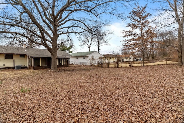 view of yard with central AC, fence, and a sunroom