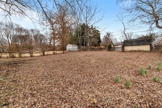 view of yard featuring an outbuilding, a storage shed, and fence