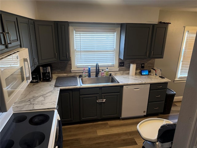 kitchen featuring white appliances, dark wood-type flooring, backsplash, and a sink