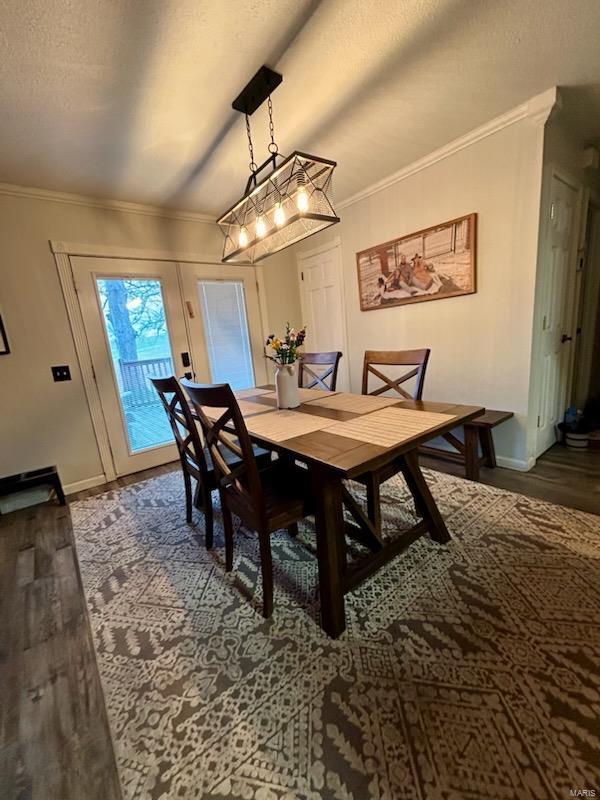 dining space featuring baseboards, a textured ceiling, wood finished floors, and crown molding