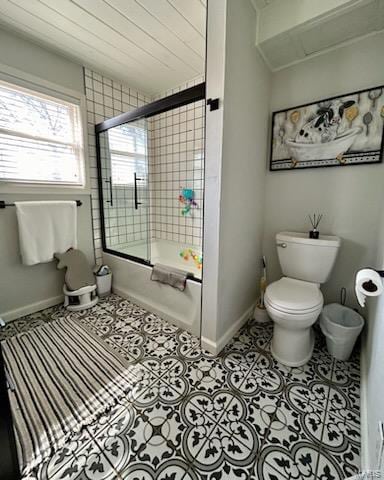 full bathroom with tile patterned floors, toilet, baseboards, and enclosed tub / shower combo