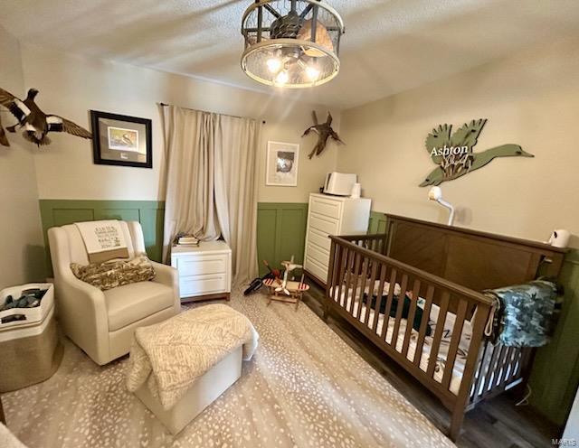 bedroom featuring wainscoting and a decorative wall