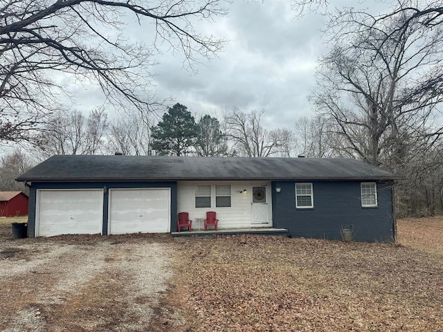 ranch-style home with a garage, dirt driveway, and brick siding