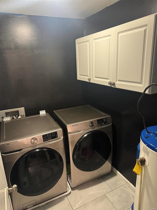 laundry room featuring cabinet space, tile patterned floors, a textured ceiling, washer and dryer, and water heater