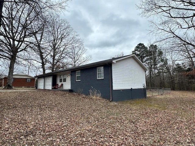 view of front of property with crawl space, an attached garage, fence, and brick siding