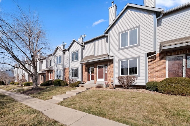 townhome / multi-family property with brick siding, a chimney, a front yard, and a residential view