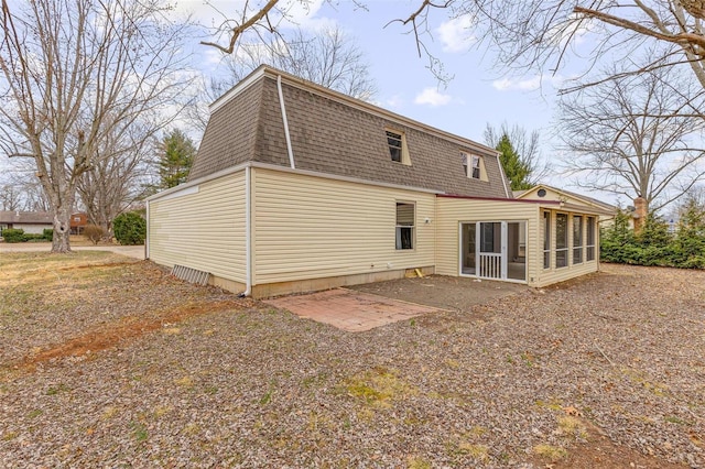 back of property featuring a sunroom, a patio area, mansard roof, and roof with shingles