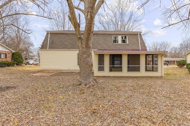 rear view of house featuring a sunroom and roof with shingles