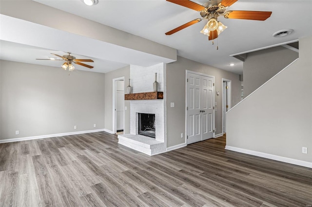 unfurnished living room featuring a fireplace, baseboards, and wood finished floors