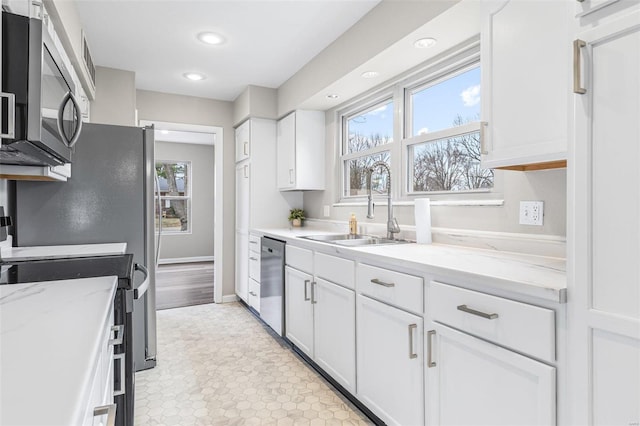 kitchen with plenty of natural light, white cabinetry, stainless steel appliances, and a sink