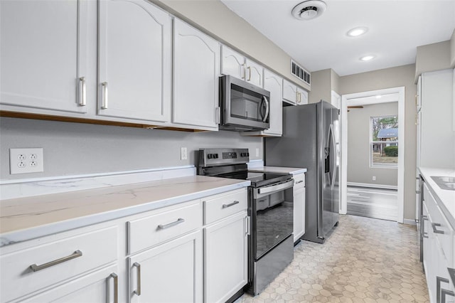 kitchen with recessed lighting, stainless steel appliances, visible vents, baseboards, and white cabinetry