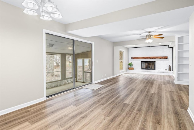 unfurnished living room featuring built in shelves, a fireplace, wood finished floors, and baseboards