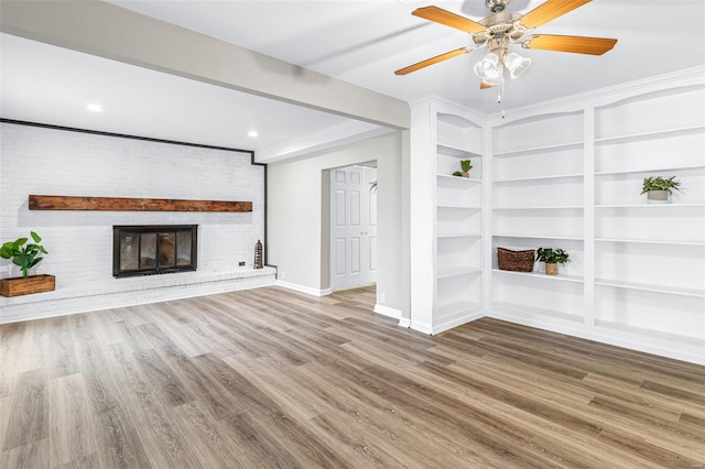 unfurnished living room featuring baseboards, a brick fireplace, wood finished floors, and built in features