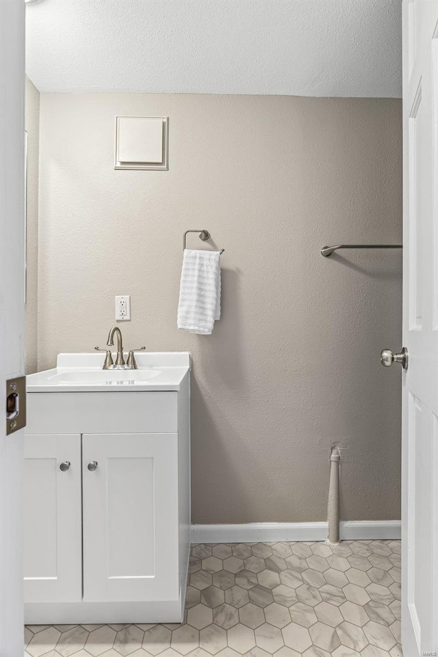 bathroom featuring a textured ceiling, vanity, and baseboards