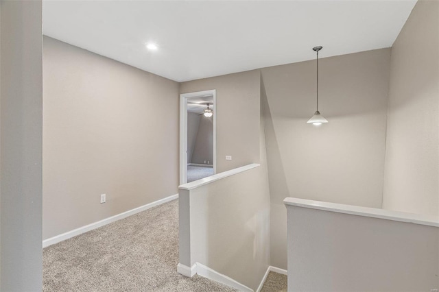 hall featuring carpet, baseboards, and an upstairs landing