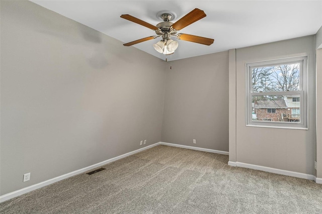 carpeted spare room featuring baseboards, visible vents, and ceiling fan