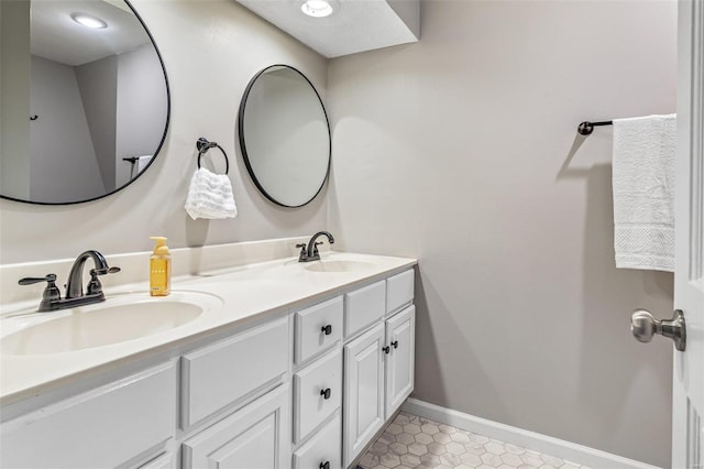 full bathroom with double vanity, tile patterned flooring, baseboards, and a sink