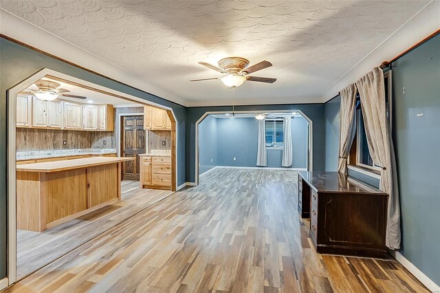 kitchen featuring arched walkways, light wood-style floors, ceiling fan, and ornamental molding