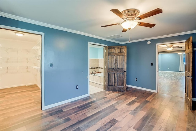 unfurnished bedroom featuring a ceiling fan, wood finished floors, baseboards, ensuite bathroom, and crown molding