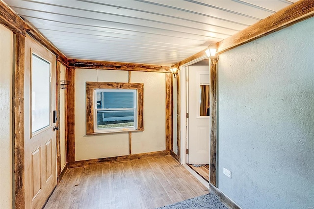 hallway featuring light wood-type flooring, wood ceiling, and a textured wall