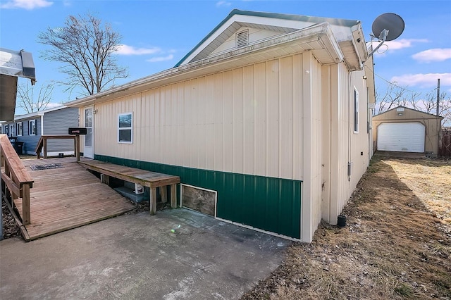 view of side of home featuring a wooden deck, a detached garage, and an outdoor structure