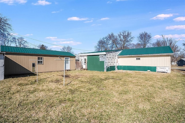 rear view of property with an outbuilding, a yard, and metal roof