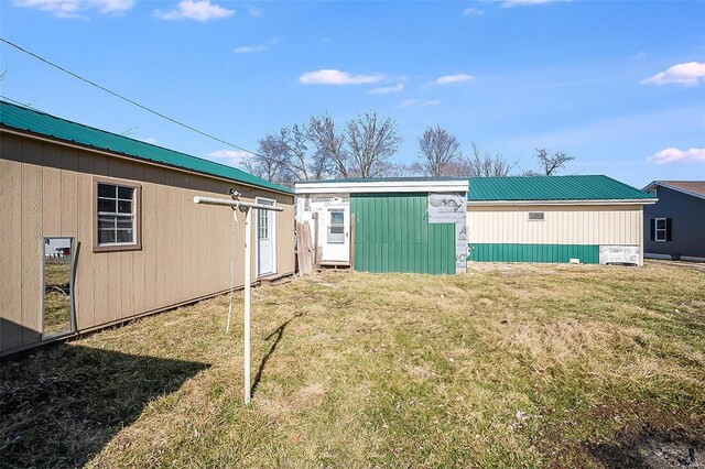 rear view of house with an outbuilding, a lawn, and metal roof