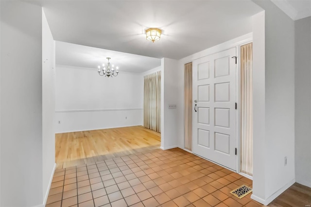 entryway featuring baseboards, an inviting chandelier, tile patterned floors, and visible vents