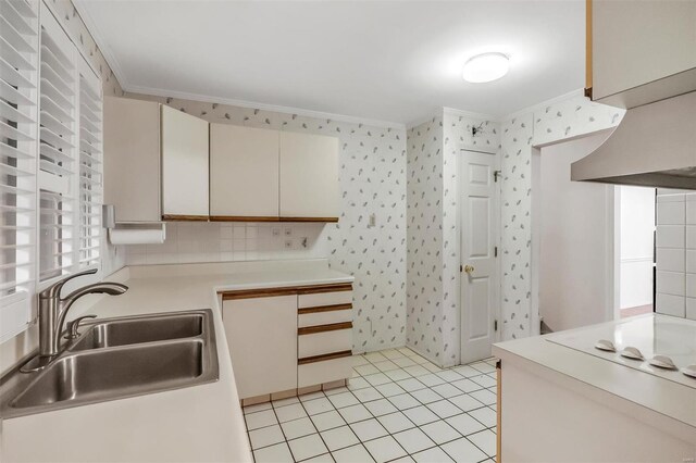 kitchen featuring crown molding, wallpapered walls, light countertops, ventilation hood, and a sink