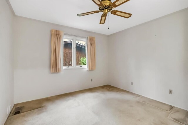 empty room with visible vents, a ceiling fan, and light colored carpet