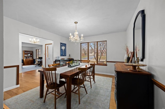 dining room with an inviting chandelier, baseboards, and light wood finished floors